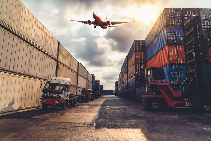 Cargo container for overseas shipping in shipyard with airplane in the sky .