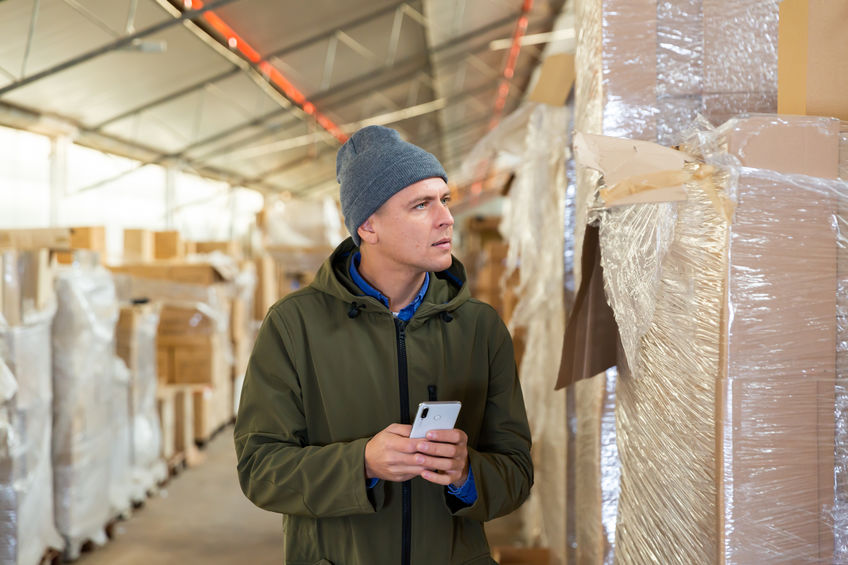 Man with a winter hat on trying to stay warm in a cold warehouse 